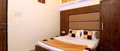 A bedroom with a wooden bed, a headboard with a textured panel, a wall-mounted light, and a door with a handle.
