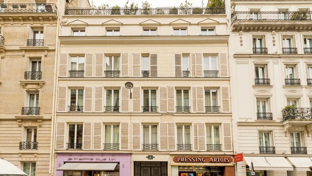 Un edificio de varios pisos con un hotel boutique llamado "Pressing Artois" en la planta baja.