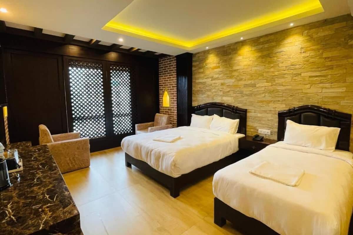 A hotel room with two beds, a desk, and a seating area.