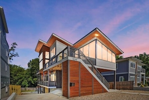 A modern two-story house with a prominent staircase, large windows, and a visible address number. - Modern Midcentury Bohemian Style gem-uptown (Charlotte)