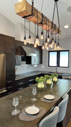 A modern kitchen with a central island, pendant lighting, and decorative vases. - Modern Midcentury Bohemian Style gem-uptown (Charlotte)