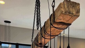 Uma sala de jantar moderna com uma mesa de madeira escura, várias luminárias e grandes janelas.