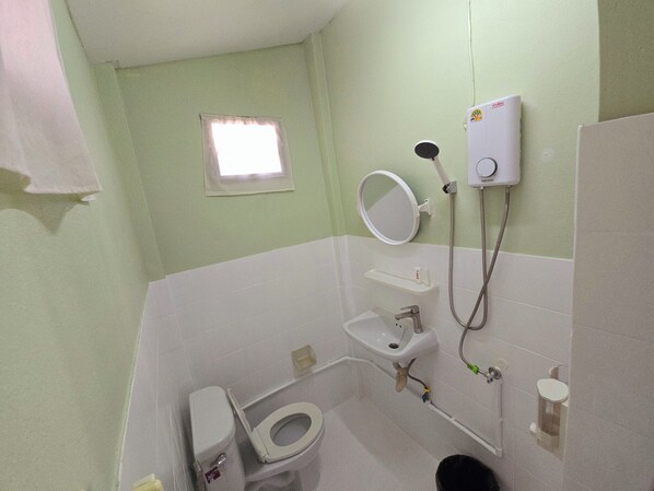 Un baño con inodoro, lavabo, espejo y ducha.