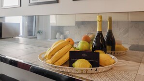 Una encimera de cocina con un frutero que contiene plátanos y limones, dos botellas de champán y una tarjeta.