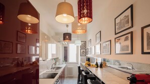 Una cocina moderna con iluminación colgante, una isla central, taburetes de bar y cuadros en las paredes.