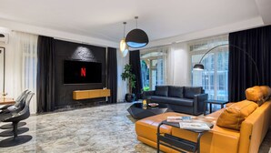 A modern living room with a flat-screen TV, a sofa, a coffee table, and a dining area with chairs. - Host Prime Paradise Villa At Rehab City (New Cairo)