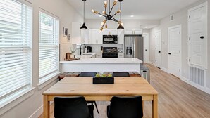 A modern kitchen with white cabinets, a central island, and pendant lighting. - Central HTX Apt: Free Wi-Fi, A/C, Full Kitchen, Near Top Attractions. (Houston)