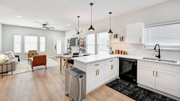 A modern kitchen with white cabinetry, a central island, pendant lighting, and a built-in dishwasher. - Central HTX Apt: Free Wi-Fi, A/C, Full Kitchen, Near Top Attractions. (Houston)