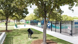 A fenced park area with playground equipment, a trash bin, and a sign indicating 'Keep Houston Safe'. - Central HTX Apt: Free Wi-Fi, A/C, Full Kitchen, Near Top Attractions. (Houston)