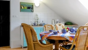 A dining area with a checkered tablecloth, wicker chairs, and a kitchen in the background. - 3 bedroom nice apartment in Huta Gorna (Huta Gorna)