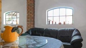 A room with a glass table, a black leather sofa, and two windows with potted plants. - 3 bedroom nice apartment in Huta Gorna (Huta Gorna)