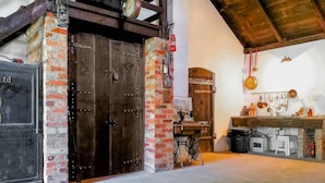 A rustic kitchen with a wooden door, brick walls, and a hanging light fixture. - 3 bedroom nice apartment in Huta Gorna (Huta Gorna)