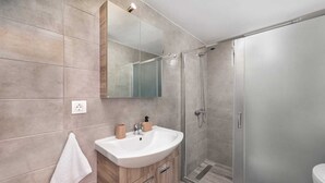Een moderne badkamer met een wastafel, spiegel en douche.