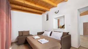 Een slaapkamer met een bed, twee slaapbanken, een houten plafond, een spiegel en een klein raam met een presentatie van fruit.