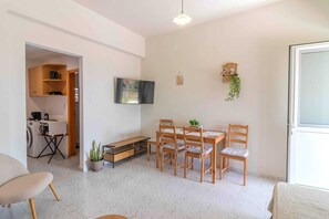 Una sala de estar moderna con comedor, televisor de pantalla plana, una planta pequeña y un mueble de madera.