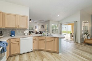 A modern kitchen with wooden cabinets, a dishwasher, and a large island.