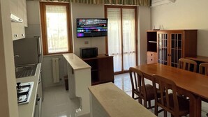 A compact kitchen with a built-in oven, a microwave, and a TV on the wall. There is a dining table with chairs and a cabinet with glass doors. - La Vedetta Holiday Home, spacious accommodation with sea view terrace (Termoli)