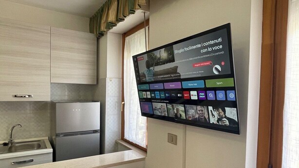 A modern kitchen with a built-in refrigerator, a sink, and a flat-screen TV mounted on the wall displaying various streaming services. - La Vedetta Holiday Home, spacious accommodation with sea view terrace (Termoli)
