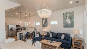 A modern living room with a sofa, coffee table, and dining area. - 3 Quarterdeck Lane (Fripp Island)