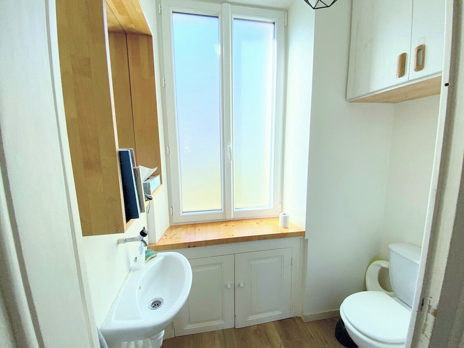Une petite salle de bain avec une fenêtre, un lavabo et des toilettes.