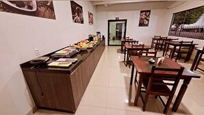A restaurant with a long counter, wooden tables, and chairs.