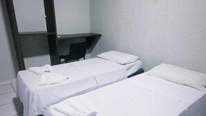 A room with two single beds, a desk, and a chair.