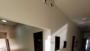 Ein geräumiger Korridor mit weißen Wänden und gefliestem Boden, mit mehreren Türen und einem an der Wand befestigten Feuerlöscher.