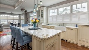 A spacious kitchen with a marble island, pendant lights, and a view of the outside through large windows. - Charming 3-bedroom house steps to Pine Point Beach with backyard oasis (Scarborough)