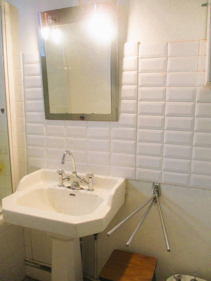 A bathroom with a white sink, a mirror, and a towel rack.