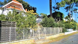 Ein Wohngebiet mit einem weißen Haus, einem eingezäunten Garten und blauem Himmel.