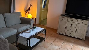 A living room with a sofa, a coffee table, a TV, and a cabinet. - Bungalow on Lake Jersleber See near Magdeburg (Barleben)