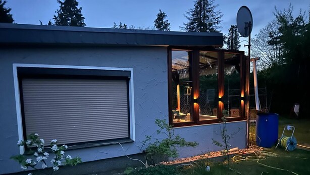 A modern house with a large garage door, a glass door leading to a patio, and a satellite dish on the roof. - Bungalow on Lake Jersleber See near Magdeburg (Barleben)