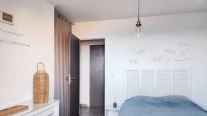 A bedroom with a bed, a bedside table, a lamp, a door, and a wall with sketches. - Appartement vue mer Entre Collioure et Cadaquès (Cerbère)