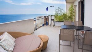 A balcony with a wicker sofa, a glass table, and a view of the sea. - Appartement vue mer Entre Collioure et Cadaquès (Cerbère)