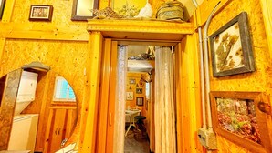 Un intérieur en bois avec un couloir menant à une salle à manger, agrémentée de tableaux encadrés et d’une petite table.