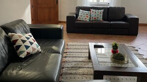 A living room with a leather sofa, a coffee table with a vase of flowers, and a patterned rug.