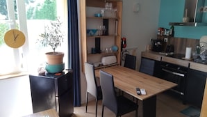 Una cocina pequeña con una mesa de madera, sillas y una planta en maceta.