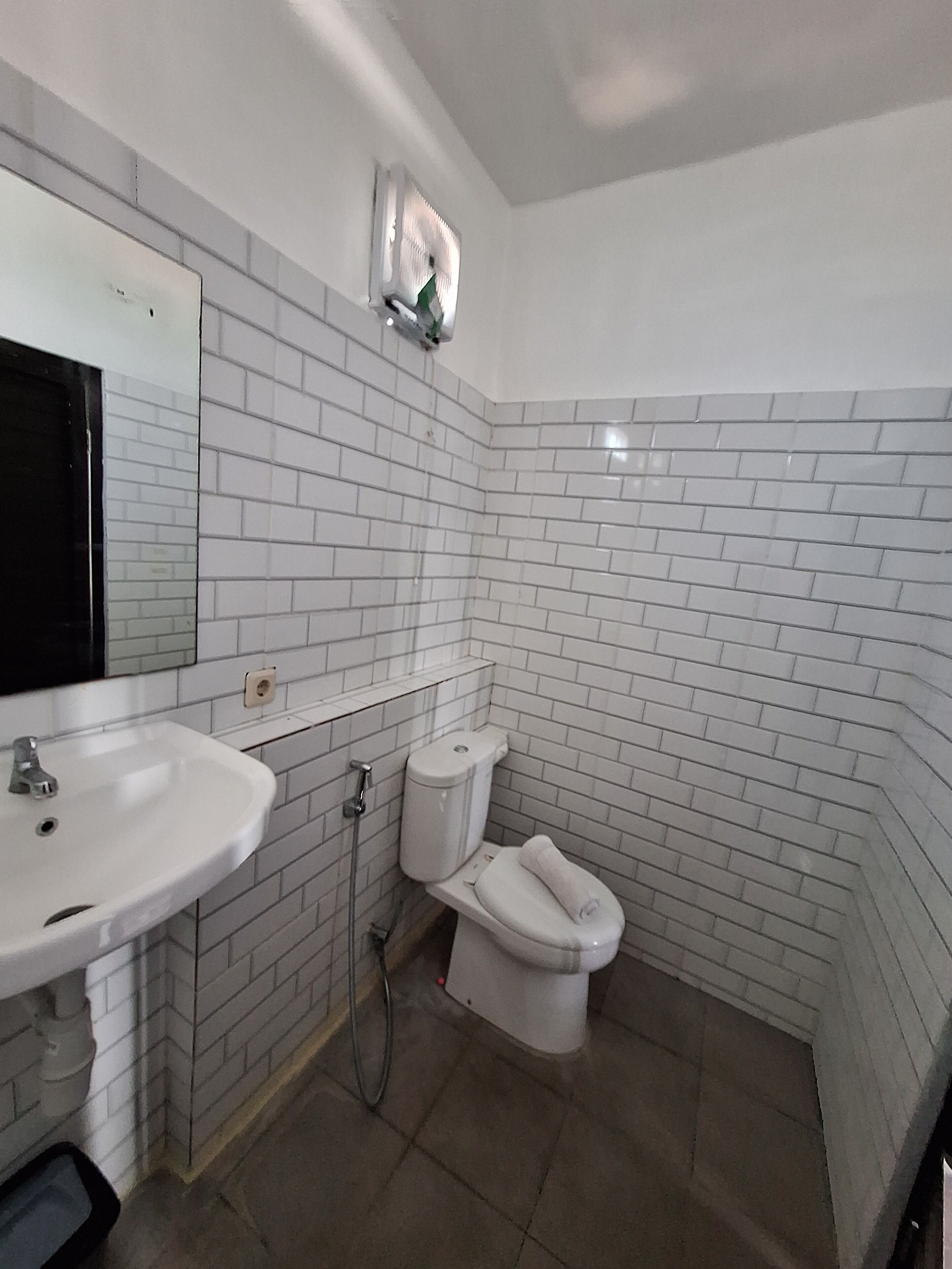 A bathroom with white tiled walls, a white sink, and a toilet.