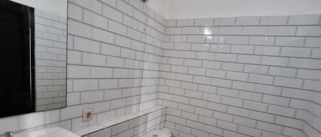A bathroom with white tiled walls, a white sink, and a toilet.