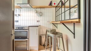 A kitchen with a built-in oven, a trash bin, and a stool. - Boase Avenue (No 69) | St Andrews (St Andrews)
