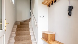 A staircase with beige carpeted steps, a wooden bench, and a wicker basket on the wall. - Boase Avenue (No 69) | St Andrews (St Andrews)