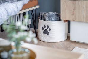 A pet bed with a paw print design, a wooden floor, and a grey wall. - Lodge No 83 | Hot Tub | Stewart's Resort Cameron (Cameron)