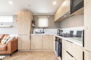 A modern kitchen with wooden cabinets, a built-in oven, and a microwave.