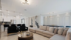 En moderne stue med en beige sofa, sorte lænestole og et sofabord.