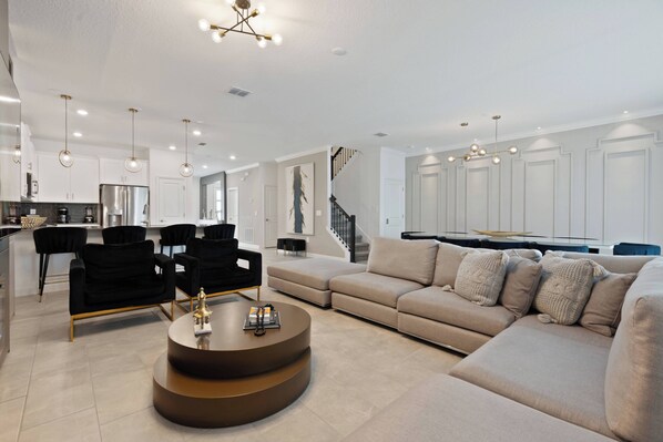 A modern living room with a beige sofa, black chairs, and a coffee table.