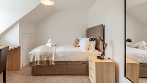 A modern bedroom with a bed, bedside table, lamp, and a large mirror. - Kinness Place (No 6) (St Andrews)