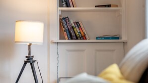 A room with a glass table, a lamp, a bookshelf, and a bed with pillows. - Kinness Place (No 6) (St Andrews)