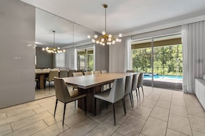 Un comedor moderno con una gran mesa de madera, varias sillas e iluminación colgante.