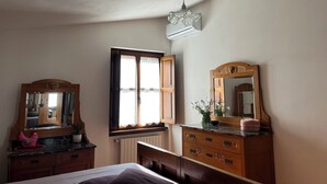 A bedroom with a bed, wooden dresser, and two mirrors. - Cozy apartment in country home a few km from Arezzo (Giovi-Ponte Alla Chiassa)