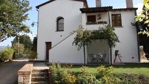 A white building with a small patio area, stone steps, and a garden. - Cozy apartment in country home a few km from Arezzo (Giovi-Ponte Alla Chiassa)